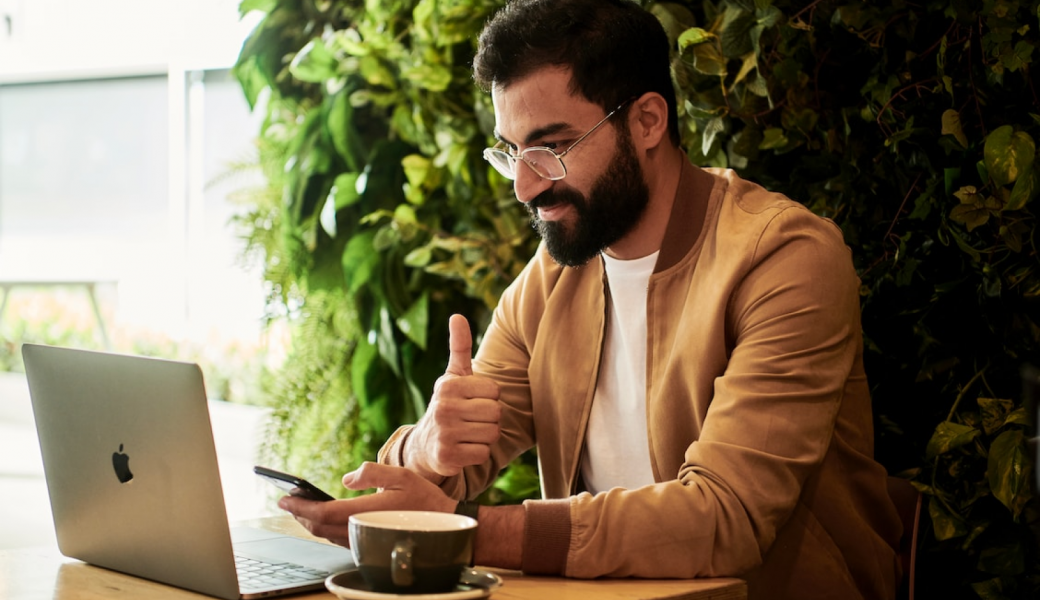 Un homme utilise un ordinateur portable et un smartphone dans un café.