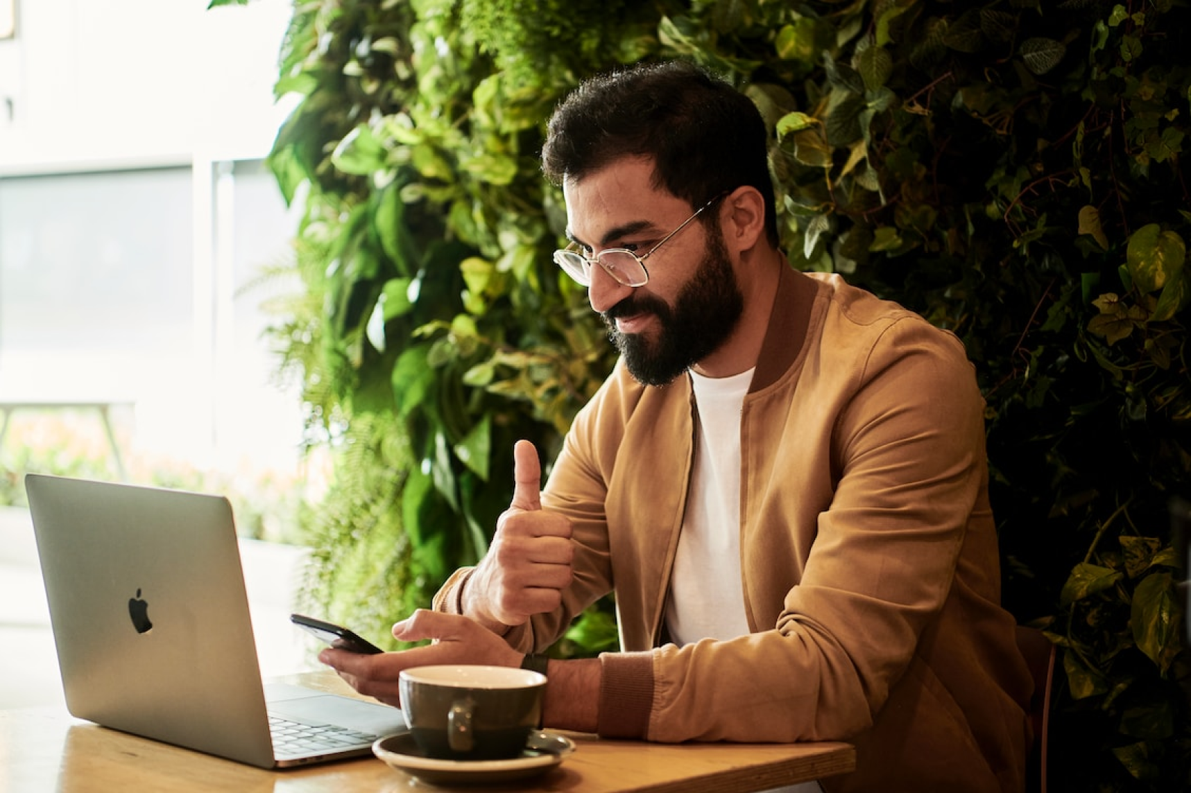 Un homme utilise un ordinateur portable et un smartphone dans un café.