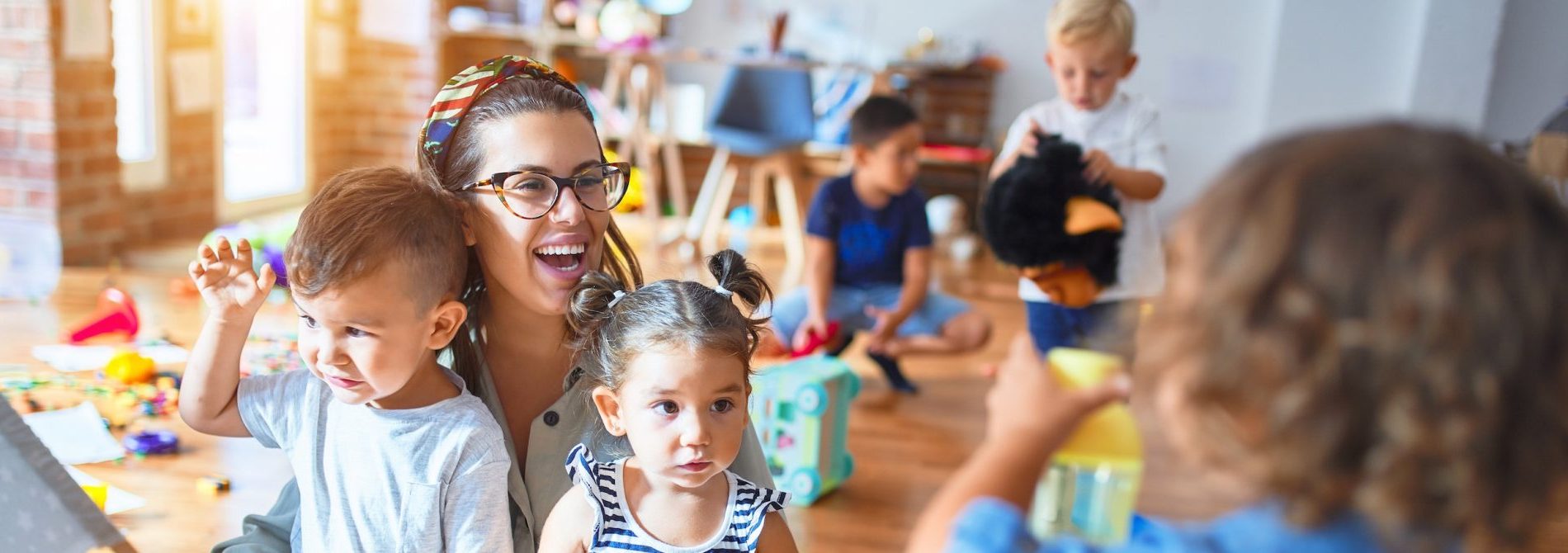 Une femme et des enfants jouent joyeusement dans une salle de classe.