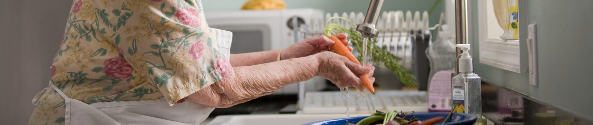 Une femme âgée prépare de la nourriture dans la cuisine.