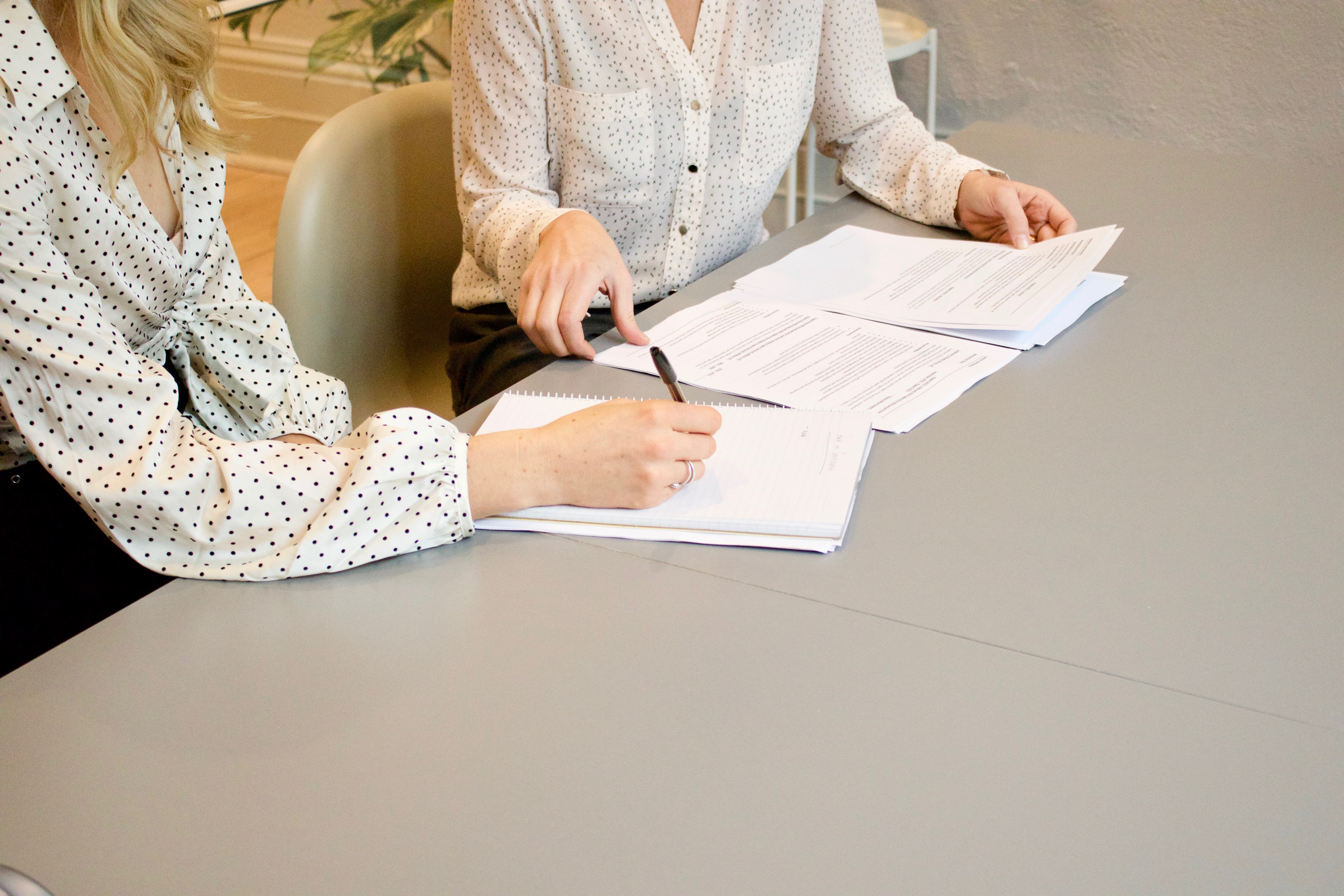 Deux femmes assises à une table signant des documents.