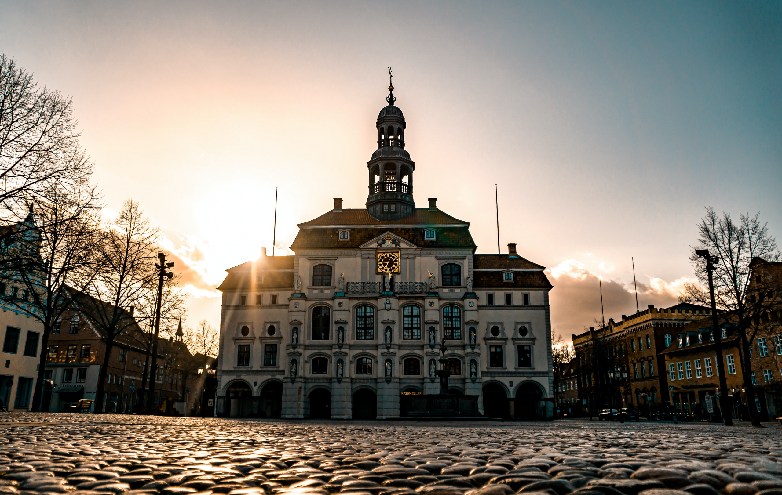 Un grand bâtiment avec une tour d'horloge au milieu d'une ville.