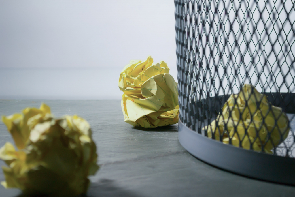 Poubelle avec des boules de papier jaune à l'intérieur et à l'extérieur.